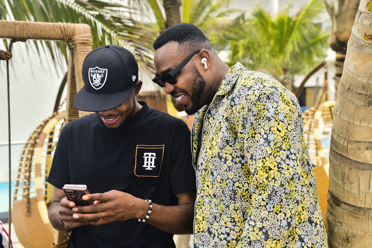 Two friends in Lagos laughing together while looking at a phone